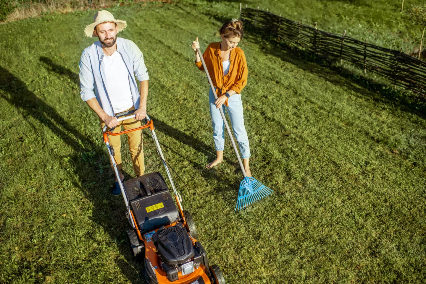 Man and woman cleaning green lawn
